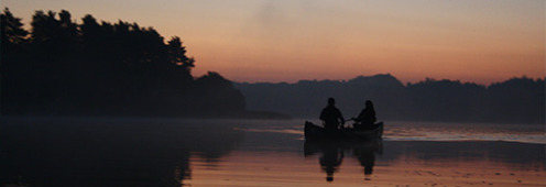Studerende i kano på en sø ved solnedgang